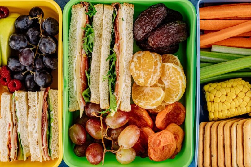 Färgglada matlådor med smörgåsar, frukt, grönsaker och snacks